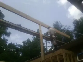 Carpenter setting a ridge beam over a new addition frame — Ice Dam Removal by Roofing Brothers in Holbrook
