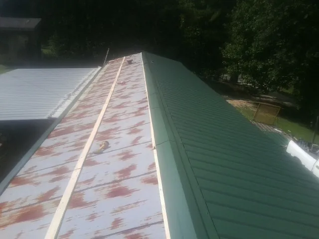 Old rusted panels beside newly installed green metal roofing — Wind Damage Roof Repair by Roofing Brothers in Holbrook