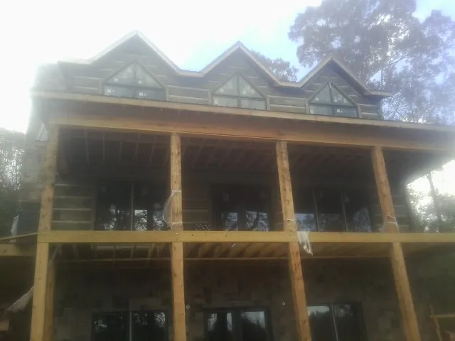 Dormers and porch framing on a large log home under construction — Roof Coating work by our crew in Holbrook